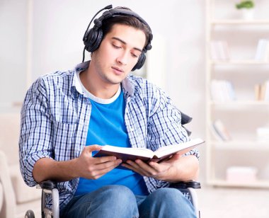 Tekerlekli sandalyede müzik dinleyen engelli adam.