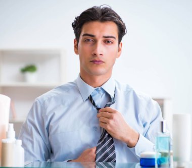 Adam banyoda çalışmak için giyiniyor.