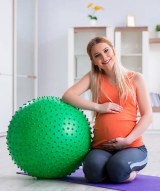 Evde doğum egzersizi yapmaya hazırlanan genç bir kadın.