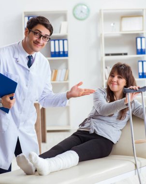 Kırık bacaklı bir hastayı muayene eden doktor.