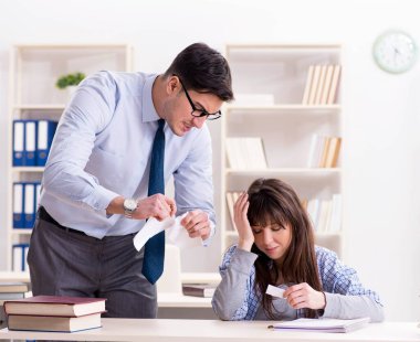 Erkek öğretim görevlisi bayan öğrenciye ders veriyor.