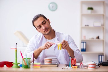 Klinikte çalışan genç erkek dişçi.