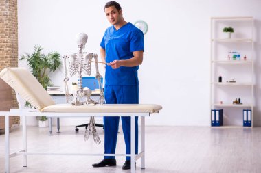 İskelet gösteren genç bir erkek doktor eğitmen.