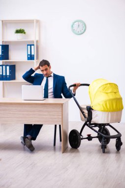 Genç erkek çalışan işyerinde çocuğa bakıyor.