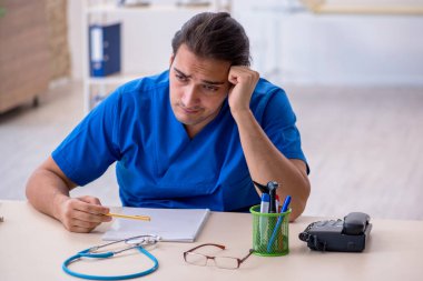 Genç erkek doktor klinikte son derece yorgun.