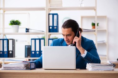 Genç yakışıklı çalışan ofiste oturuyor.