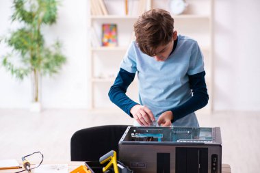 Çocuk atölyede bilgisayar tamir ediyor.