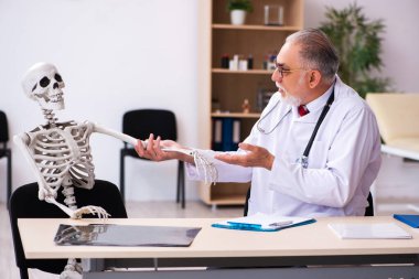 Klinikteki yaşlı erkek doktor ve iskelet hastası.