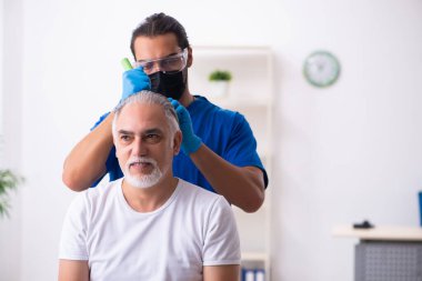 Yaşlı adam saç nakli için genç erkek doktoru ziyaret ediyor.