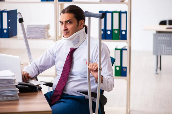 Leg injured male employee with crutches at workplace — Stock Photo, Image