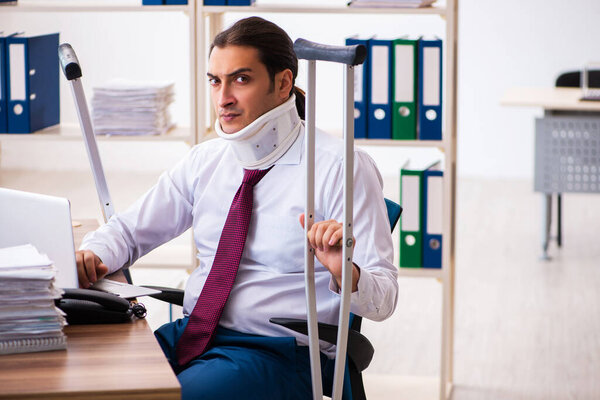 Leg injured male employee with crutches at workplace