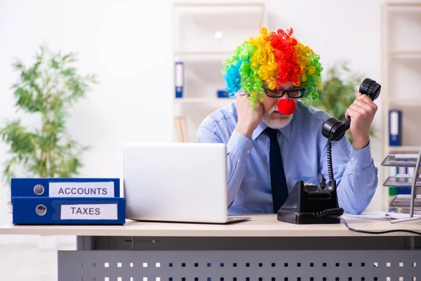 Old businessman clown working in the office