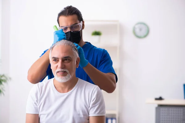 Old man visiting young male doctor in hair transplantation conce — Stock Photo, Image