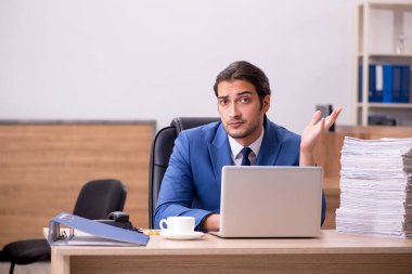 Ofisteki aşırı işten memnun olmayan genç bir erkek işçi.