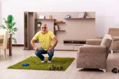 Yaşlı adam evde spor egzersizleri yapıyor.