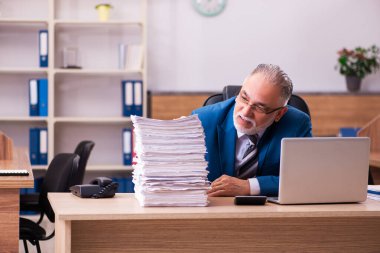 Ofisteki aşırı işten memnun olmayan yaşlı bir erkek işçi.