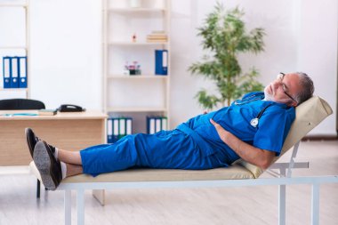 Yaşlı erkek doktor gece vardiyasından sonra çok yorgun.