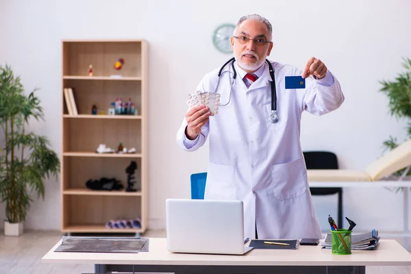 Velho médico masculino segurando cartão de crédito — Fotografia de Stock