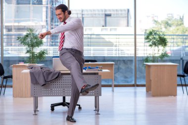 Genç erkek çalışan ofiste spor egzersizleri yapıyor.