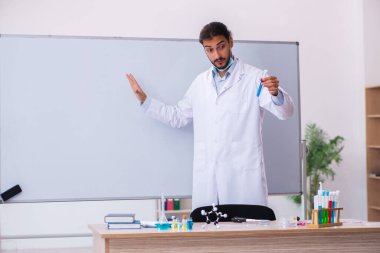 Sınıfta oturan genç erkek kimya öğretmeni.
