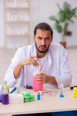 Genç erkek kimyager laboratuarda sabun test ediyor.