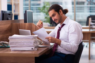 Genç bir erkek işçi ve ofiste çok fazla iş var.