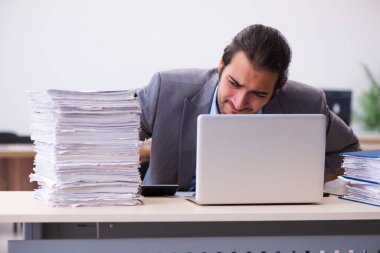 Ofisteki aşırı işten memnun olmayan genç bir erkek işçi.