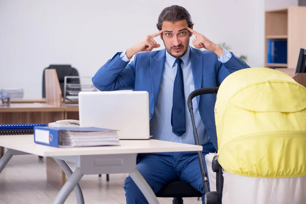 Young male employee looking after new born at workplace