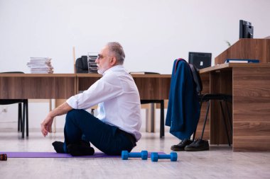 Ofiste spor egzersizleri yapan eski bir işadamı.
