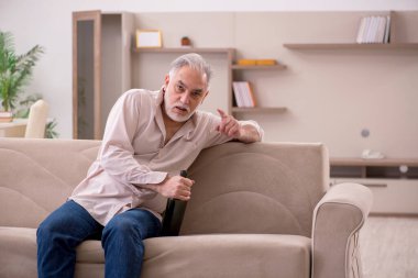 Yaşlı adam evde alkol içiyor.