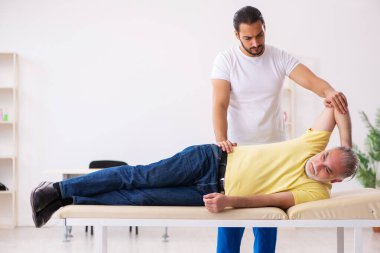 Yaşlı erkek hasta, genç erkek doktor masörünü ziyaret ediyor.