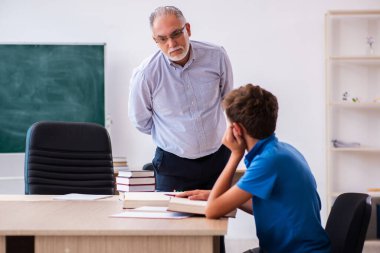 Yaşlı erkek öğretmen ve okul çocuğu sınıfta.