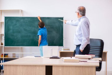 Yaşlı erkek öğretmen ve okul çocuğu sınıfta.