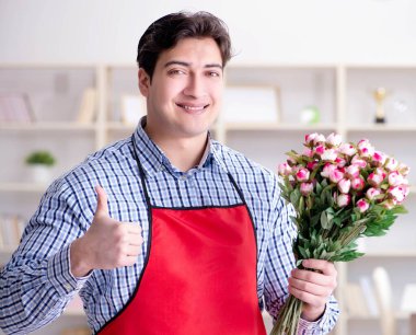 Çiçekçi asistanı bir demet çiçek veriyor.