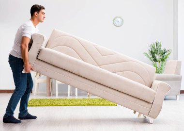 Genç adam evde mobilya taşıyor.