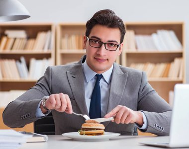 Aç komik iş adamı abur cubur sandviç yiyor.