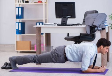 İş adamı tatilde ofiste spor yapıyor.