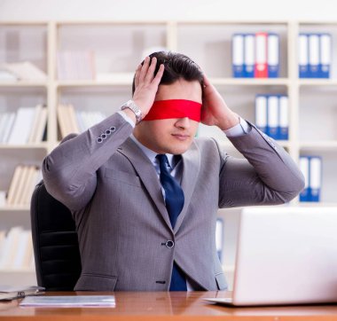 Ofiste masasında oturan gözü bağlı iş adamı.