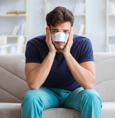 Genç adam estetik cerrahi burnundan sonra evde iyileşiyor.