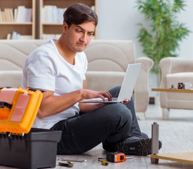 Adam evde mobilya montajı yapıyor.