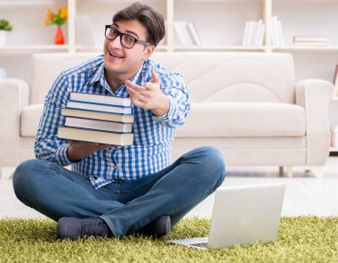 Genç yakışıklı adam evde yerde oturuyor.