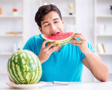 Evde karpuz yiyen bir adam.