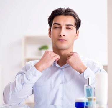 Adam banyoda çalışmak için giyiniyor.