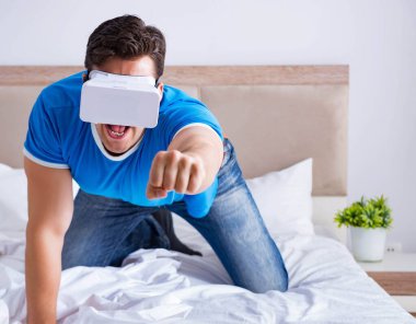 Yatakta sanal gerçeklik başlığı takan genç bir adam.