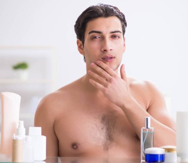 Genç adam banyoda çalışmak için hazırlanıyor.