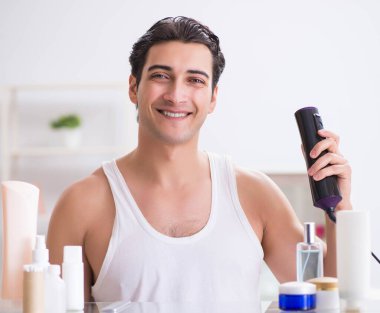 Genç adam sabah saçlarını kurutuyor.