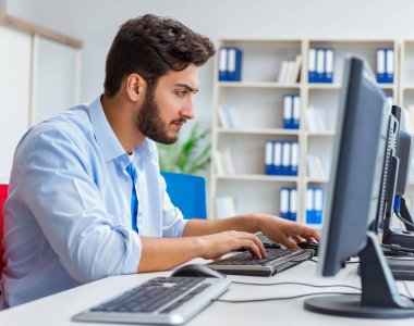 Birçok ekranın önünde oturan bir iş adamı