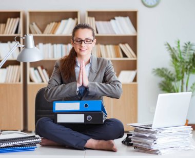 İş kadını ofiste meditasyon yapıyor.