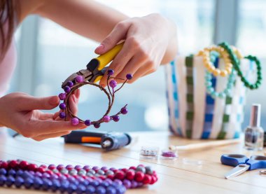 Kadın evde mücevher yapıyor.