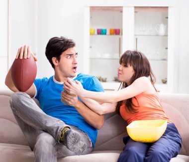 Adam karısıyla Amerikan futbolu seyrediyor.